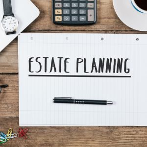 Estate Planning text, Office desk with computer technology, high Estate Planning text on note pad, office desk with electronic devices, computer and paper, wood table from above, concept image for blog title or header image.